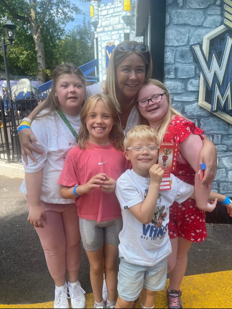 A group of smiling children and an adult at Gulliver’s World, holding a ride access pass.